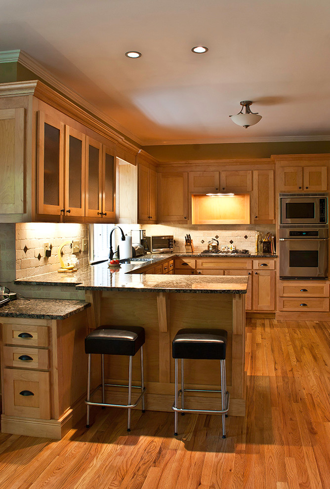 Mid-sized transitional l-shaped light wood floor eat-in kitchen photo in Atlanta with a double-bowl sink, recessed-panel cabinets, light wood cabinets, granite countertops, beige backsplash, stone tile backsplash, stainless steel appliances and a peninsula