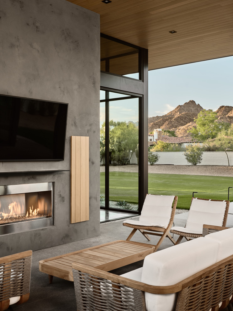 Modern courtyard patio in Phoenix with with fireplace, concrete slab and a roof extension.