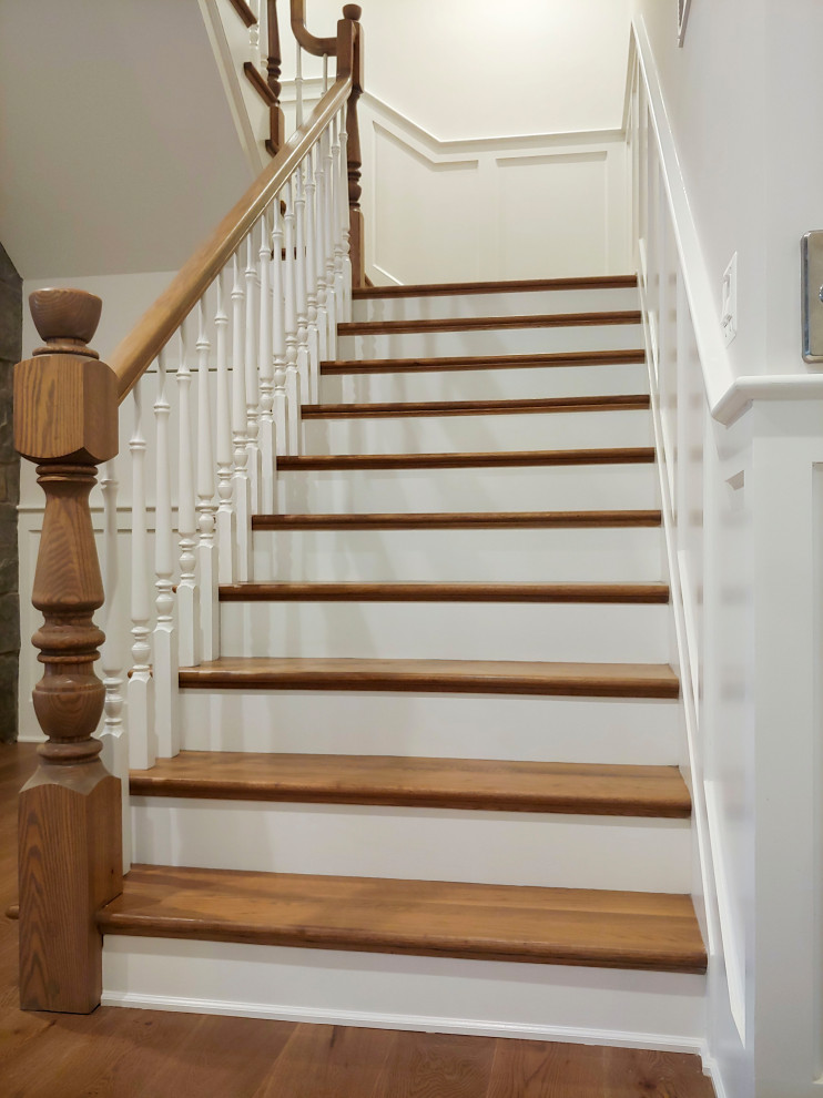 This is an example of a medium sized classic wood u-shaped wood railing staircase in DC Metro with painted wood risers and wainscoting.