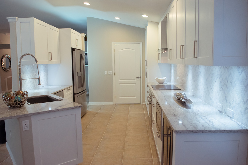 Example of a mid-sized transitional galley ceramic tile and beige floor eat-in kitchen design in Miami with an undermount sink, shaker cabinets, white cabinets, granite countertops, gray backsplash, stone tile backsplash, stainless steel appliances and a peninsula