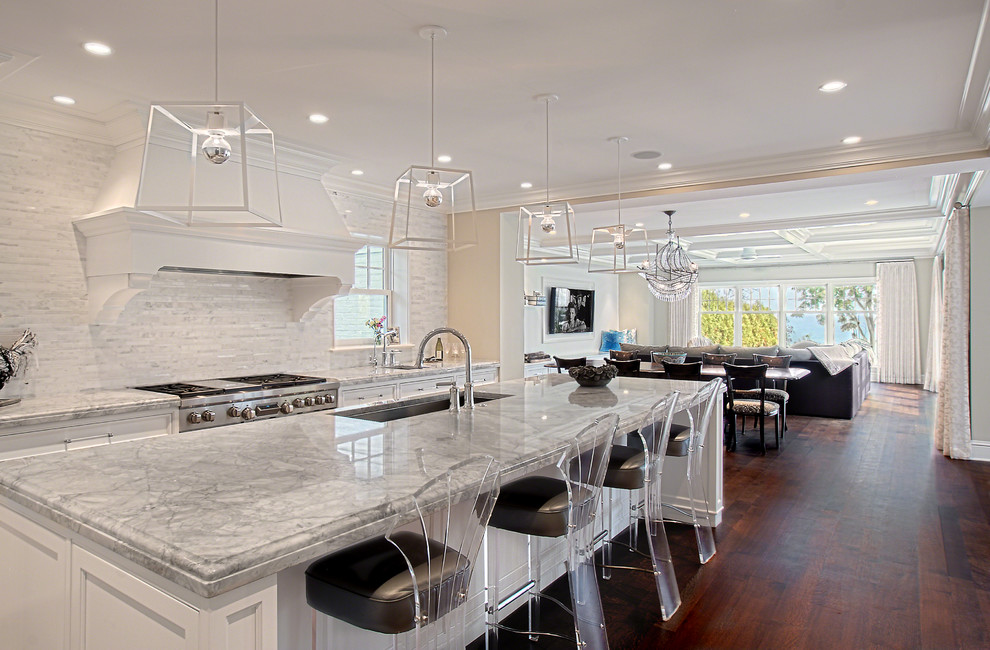Huge transitional u-shaped dark wood floor and brown floor kitchen photo in Chicago with white cabinets, quartzite countertops, white backsplash, stone tile backsplash, an island, an undermount sink, stainless steel appliances, gray countertops and recessed-panel cabinets
