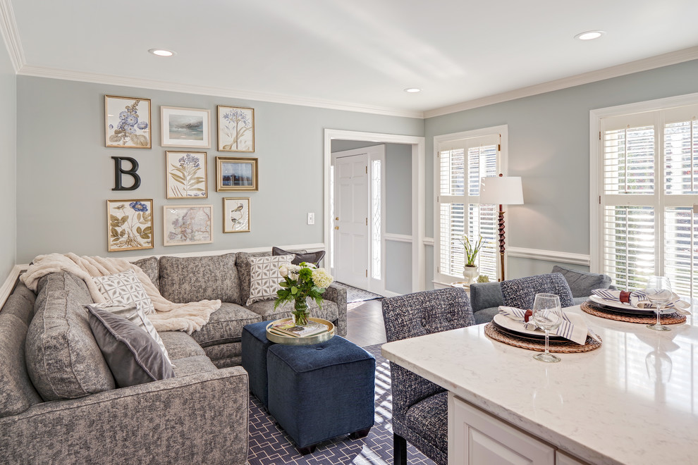 Example of a mid-sized transitional u-shaped medium tone wood floor and brown floor eat-in kitchen design with a farmhouse sink, raised-panel cabinets, white cabinets, quartz countertops, blue backsplash, porcelain backsplash, paneled appliances and an island