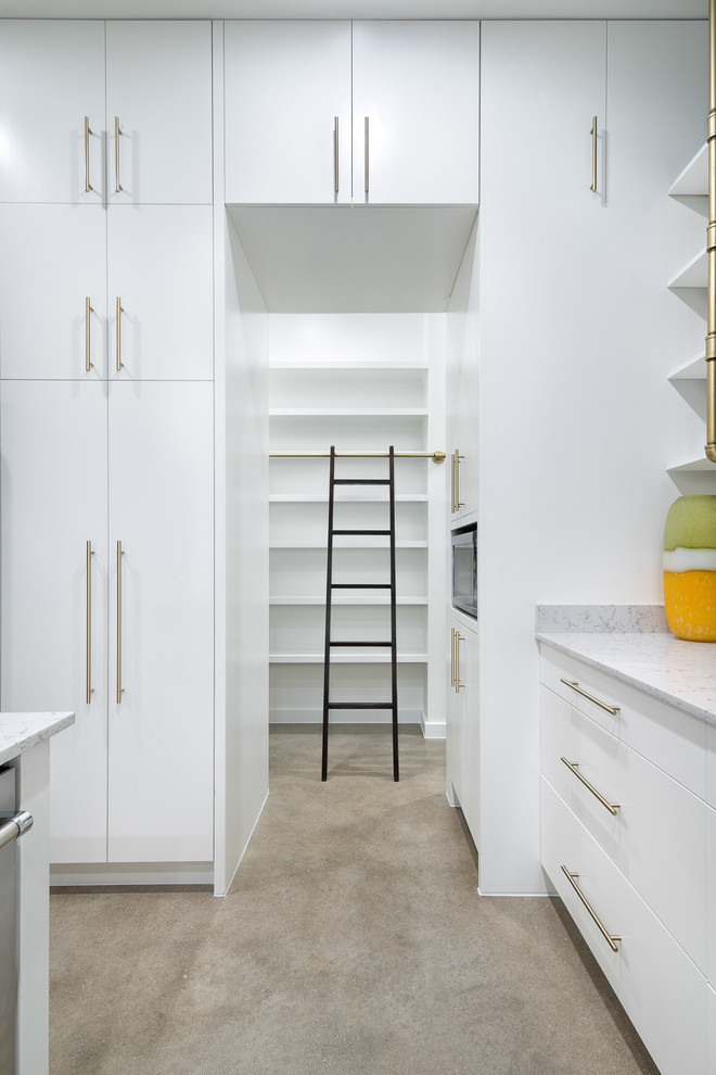 Large midcentury u-shaped kitchen pantry in Austin with a drop-in sink, flat-panel cabinets, white cabinets, laminate benchtops, white splashback, stainless steel appliances, concrete floors, with island, brown floor and grey benchtop.