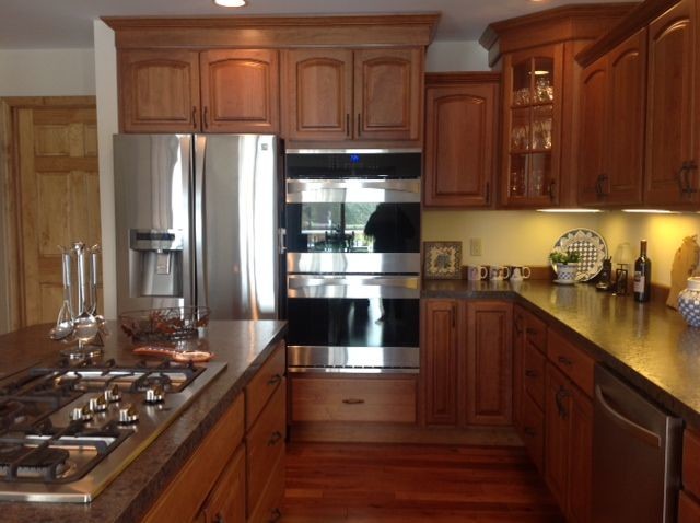 This is an example of a traditional eat-in kitchen in Other with a double-bowl sink, raised-panel cabinets, medium wood cabinets, quartz benchtops, stainless steel appliances, medium hardwood floors and with island.