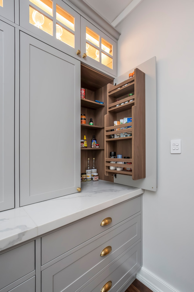 Large u-shaped kitchen pantry in Sydney with a submerged sink, shaker cabinets, grey cabinets, engineered stone countertops, window splashback, black appliances, dark hardwood flooring, an island, brown floors, white worktops and a drop ceiling.