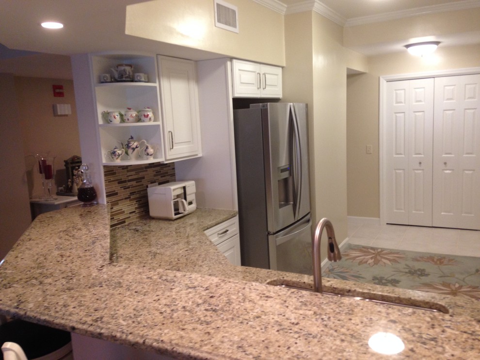 Open concept kitchen - mid-sized l-shaped ceramic tile open concept kitchen idea in Miami with an undermount sink, raised-panel cabinets, white cabinets, granite countertops, brown backsplash, glass tile backsplash, stainless steel appliances and a peninsula