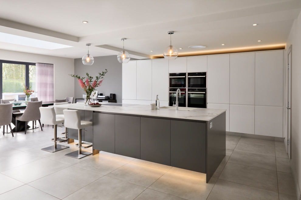 Inspiration for a large contemporary open plan kitchen in Buckinghamshire with an integrated sink, grey cabinets, laminate benchtops, black appliances, ceramic floors, with island, grey floor and white benchtop.