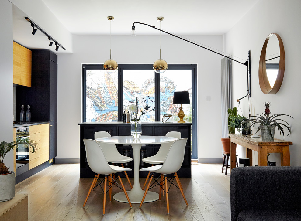 This is an example of a contemporary open plan dining in London with white walls and light hardwood floors.