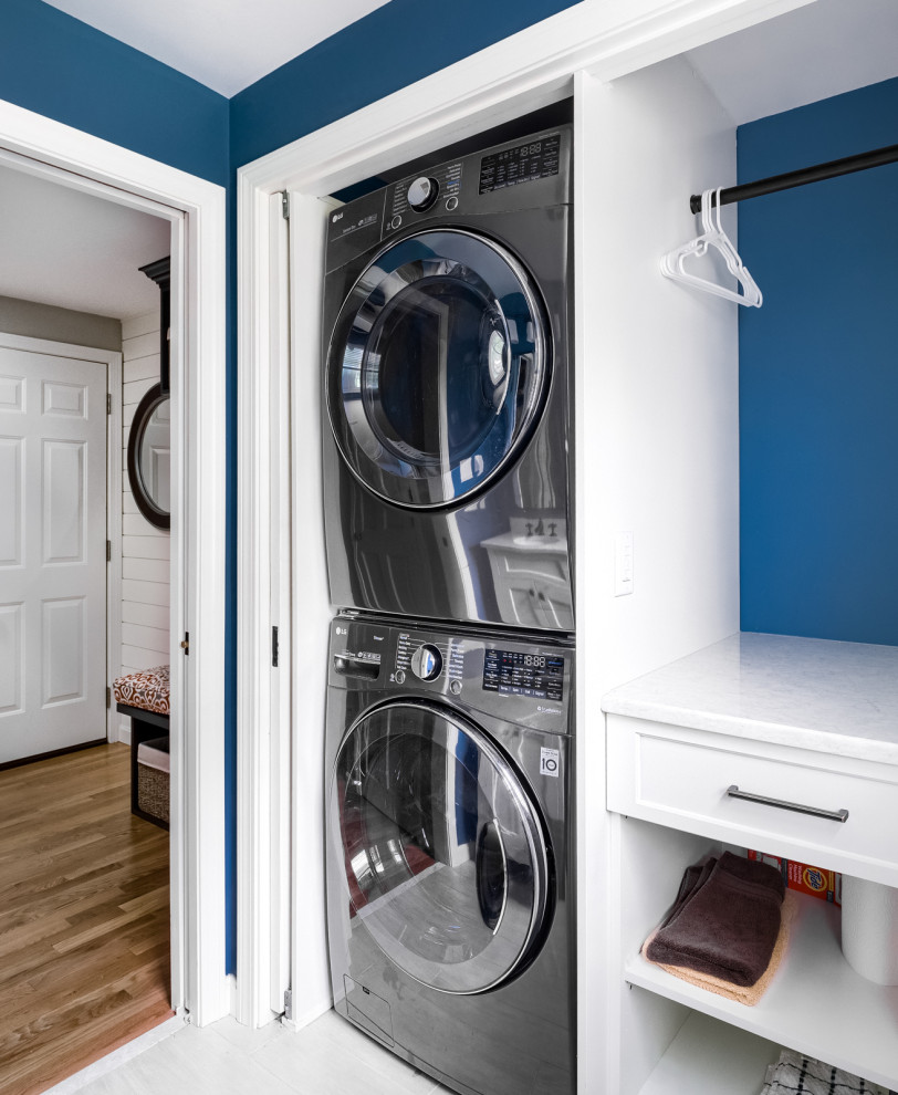 Idee per una piccola lavanderia multiuso design con pareti blu, lavatrice e asciugatrice a colonna e pavimento bianco
