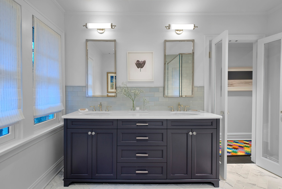 Идея дизайна: главная ванная комната среднего размера в стиле неоклассика (современная классика) с фасадами с утопленной филенкой, синими фасадами, отдельно стоящей ванной, угловым душем, серой плиткой, плиткой кабанчик, мраморным полом, врезной раковиной, столешницей из кварцита, белым полом, душем с распашными дверями, белой столешницей, тумбой под две раковины и встроенной тумбой