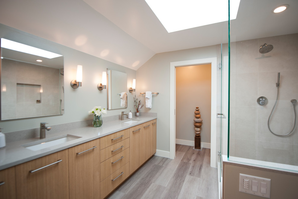 This is an example of a mid-sized scandinavian master bathroom in Seattle with flat-panel cabinets, light wood cabinets, a corner shower, a one-piece toilet, beige tile, ceramic tile, grey walls, vinyl floors, engineered quartz benchtops, grey floor, a hinged shower door and grey benchtops.
