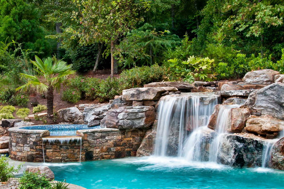 Photo of a traditional natural pool in Other with a water feature.