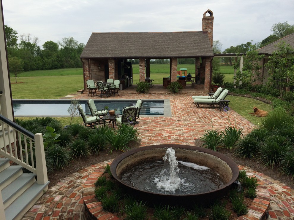 This is an example of a mid-sized traditional backyard rectangular lap pool in New Orleans with brick pavers.