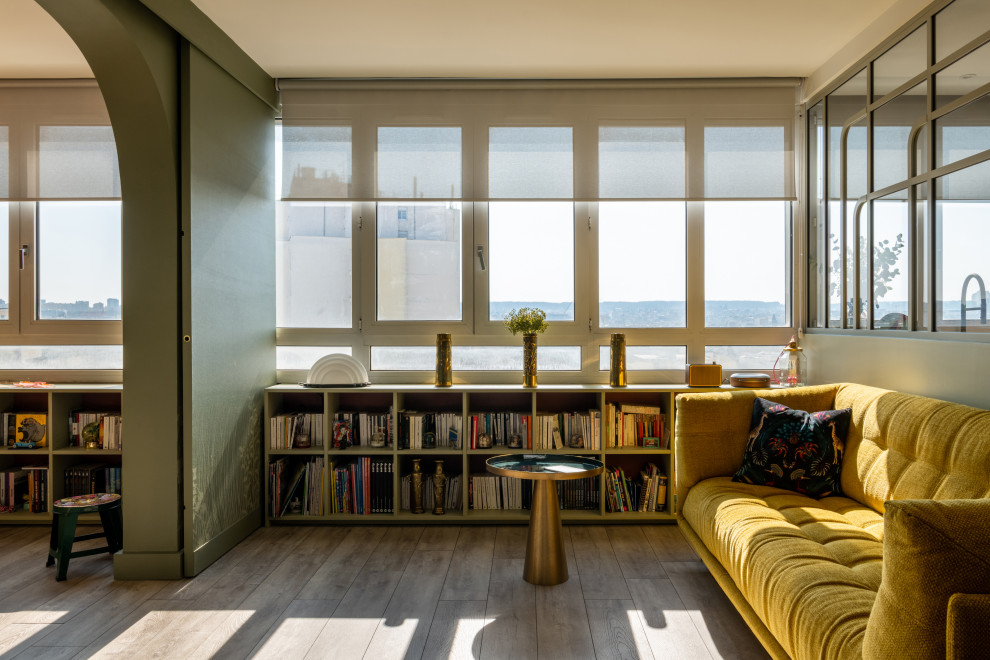 Cette photo montre un petit salon tendance ouvert avec une bibliothèque ou un coin lecture, un mur vert, parquet clair, aucune cheminée, aucun téléviseur, un sol marron et du papier peint.