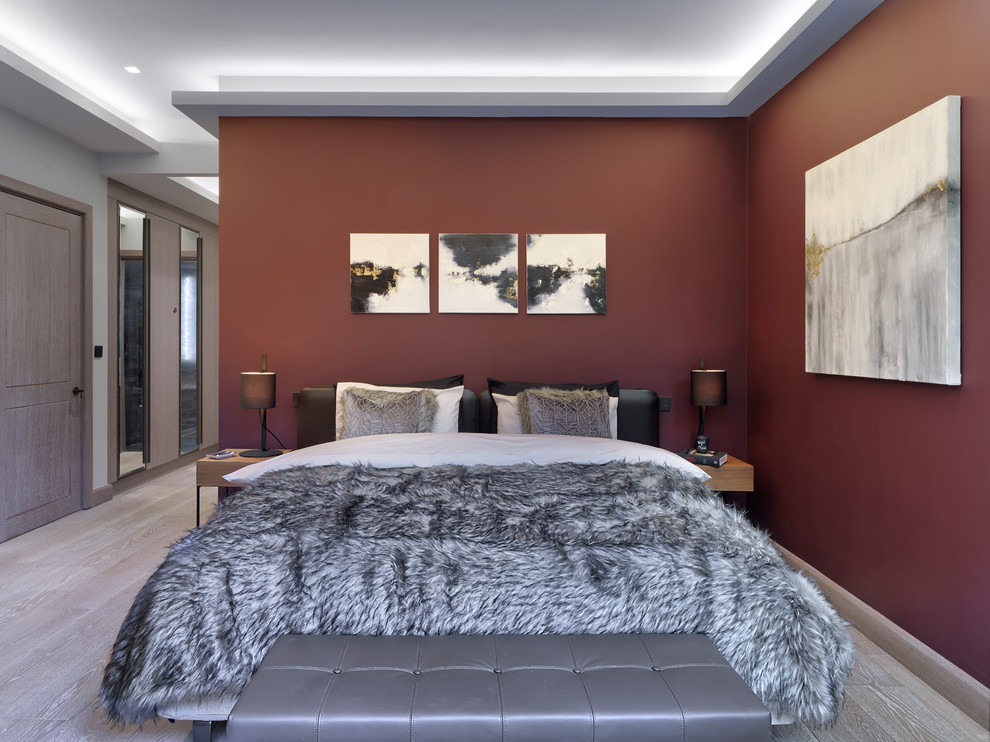 This is an example of a contemporary bedroom in London with red walls, light hardwood floors and beige floor.