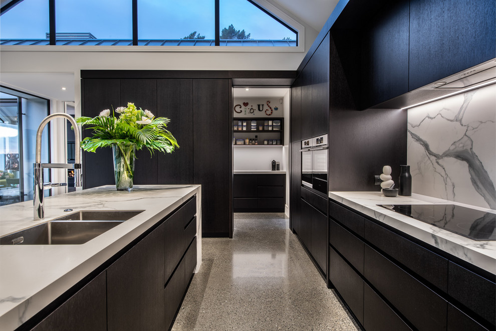 Design ideas for a large contemporary galley eat-in kitchen in Auckland with a drop-in sink, flat-panel cabinets, dark wood cabinets, multi-coloured splashback, porcelain splashback, stainless steel appliances, concrete floors, with island and grey floor.