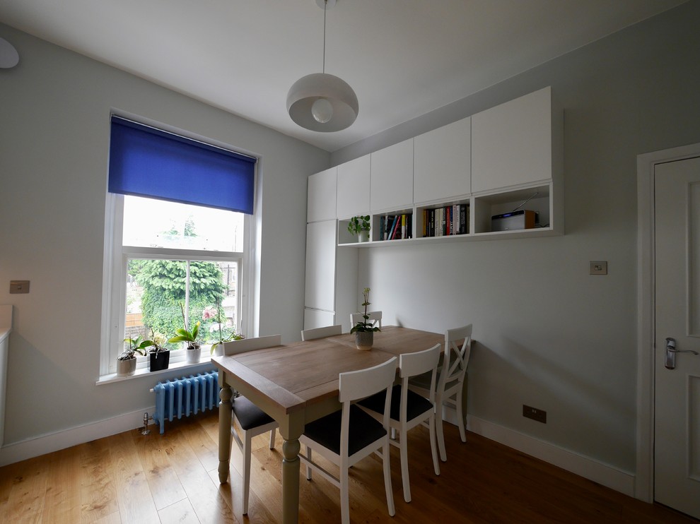 This is an example of a mid-sized contemporary l-shaped separate kitchen in London with an undermount sink, flat-panel cabinets, white cabinets, quartzite benchtops, blue splashback, stainless steel appliances, light hardwood floors, beige floor and white benchtop.
