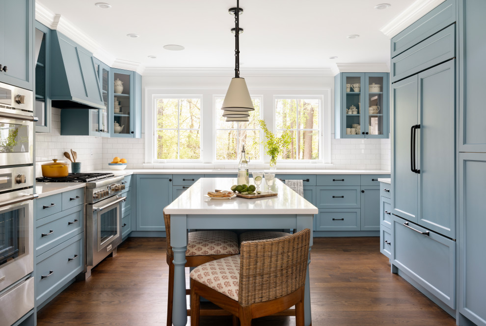 Design ideas for an expansive traditional u-shaped eat-in kitchen in Portland with an undermount sink, beaded inset cabinets, blue cabinets, quartz benchtops, white splashback, ceramic splashback, stainless steel appliances, medium hardwood floors, with island and white benchtop.