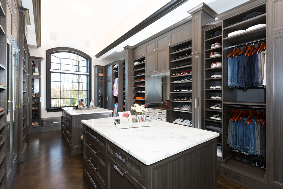 Inspiration for a large transitional gender-neutral walk-in wardrobe in New York with recessed-panel cabinets, grey cabinets, dark hardwood floors and brown floor.