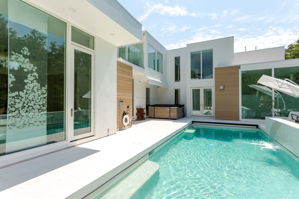 Modelo de piscina infinita contemporánea de tamaño medio rectangular en patio con privacidad y adoquines de hormigón