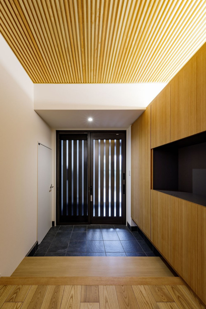 Geräumiger Eingang mit Korridor, weißer Wandfarbe, Keramikboden, Schiebetür, schwarzer Haustür, grauem Boden, Kassettendecke und Tapetenwänden in Osaka