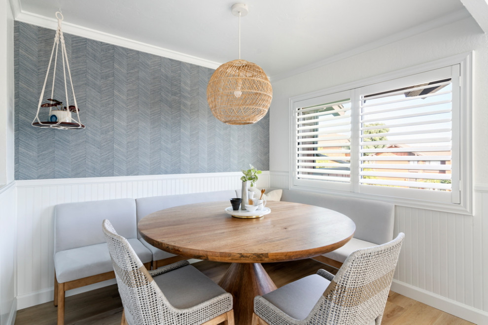 Esempio di una piccola sala da pranzo aperta verso la cucina stile marinaro con pareti blu, pavimento in laminato e carta da parati