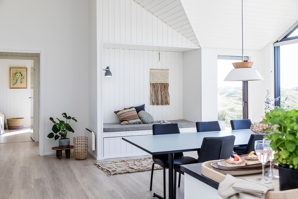 This is an example of a mid-sized scandinavian dining room in Other with white walls, light hardwood floors, a wood stove and brown floor.