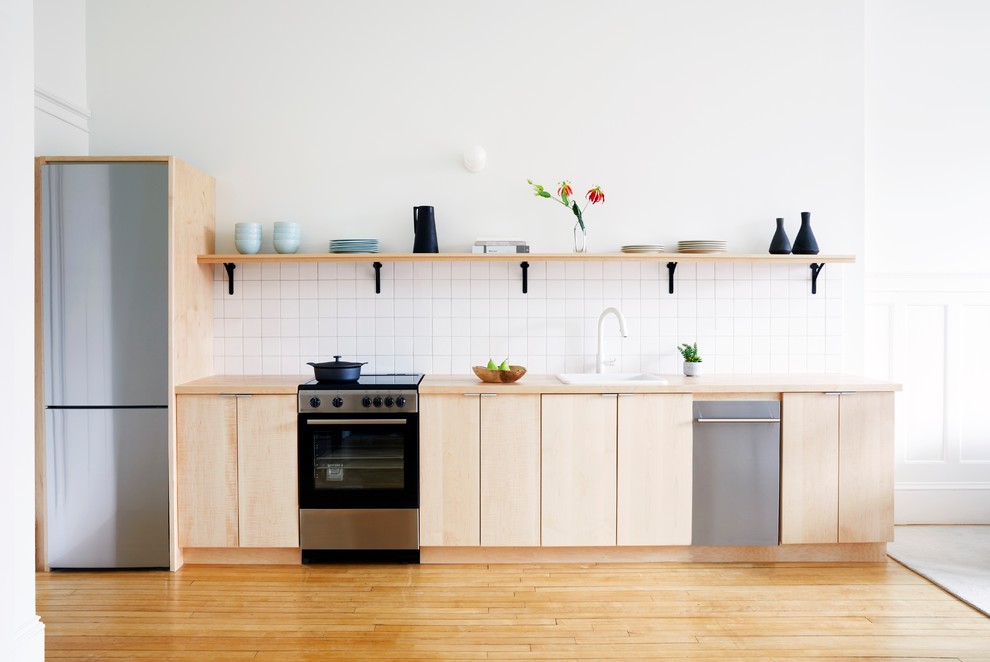 Inspiration for a small scandinavian single-wall eat-in kitchen in Providence with a drop-in sink, flat-panel cabinets, light wood cabinets, wood benchtops, white splashback, porcelain splashback, stainless steel appliances, light hardwood floors, no island and beige floor.