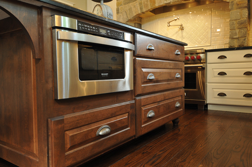 Inspiration for a rustic l-shaped eat-in kitchen remodel in Chicago with a farmhouse sink, raised-panel cabinets, dark wood cabinets, soapstone countertops, white backsplash, subway tile backsplash and paneled appliances
