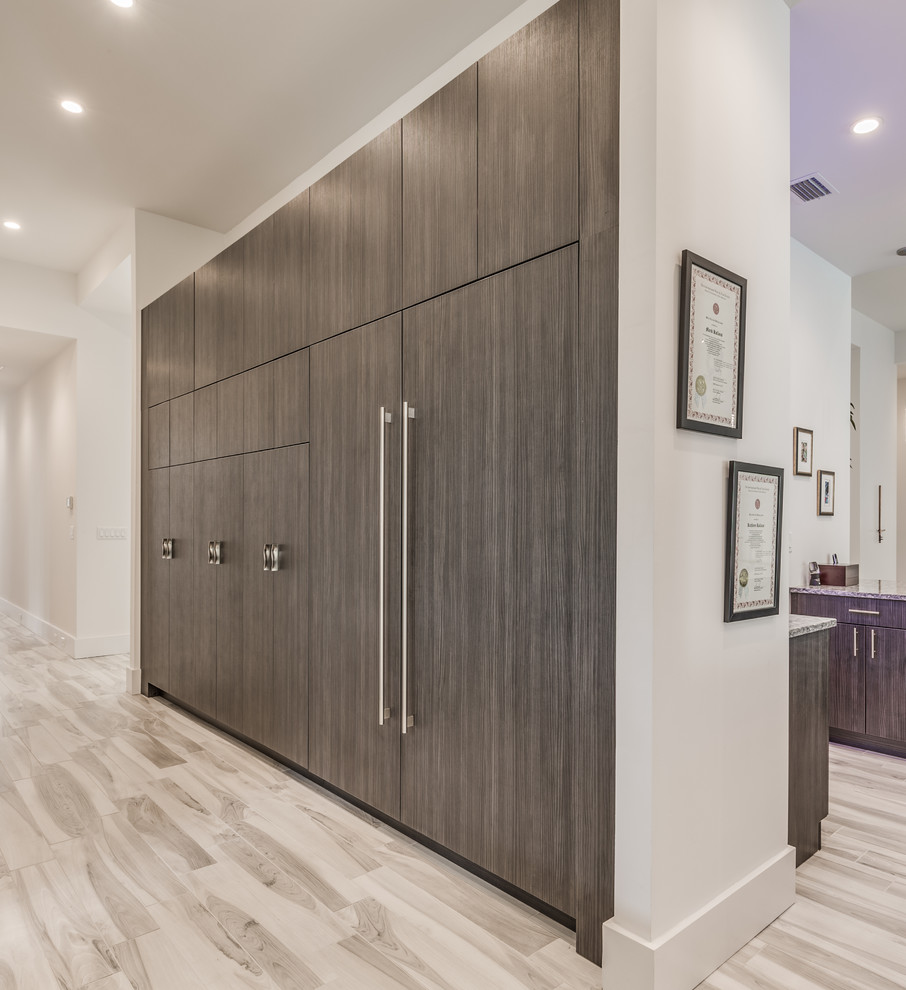 This is an example of a large contemporary storage and wardrobe in Jacksonville with flat-panel cabinets, white cabinets, porcelain floors and grey floor.