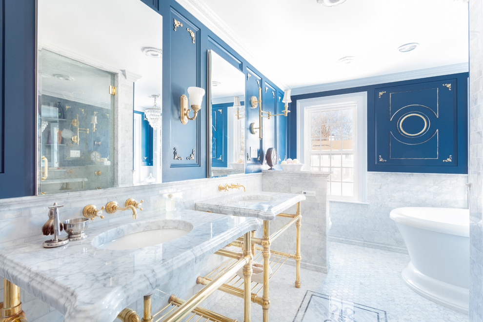 This is an example of a mid-sized traditional master bathroom in Boston with a freestanding tub, marble, blue walls, marble floors, an undermount sink, marble benchtops, white tile, white floor and white benchtops.