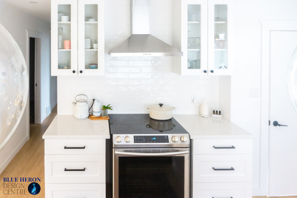 Photo of a medium sized scandi l-shaped kitchen/diner in Other with a submerged sink, shaker cabinets, white cabinets, engineered stone countertops, white splashback, metro tiled splashback, stainless steel appliances, an island, beige floors and white worktops.
