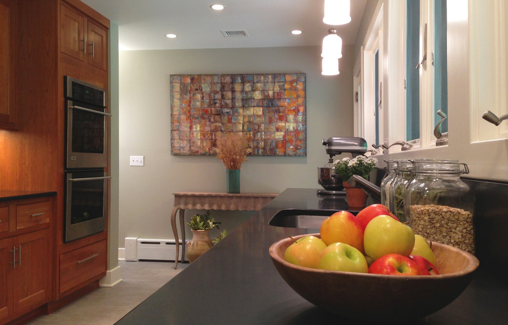 Mid-sized transitional galley gray floor and porcelain tile eat-in kitchen photo in New York with an undermount sink, shaker cabinets, medium tone wood cabinets, granite countertops, red backsplash, brick backsplash, stainless steel appliances, no island and black countertops