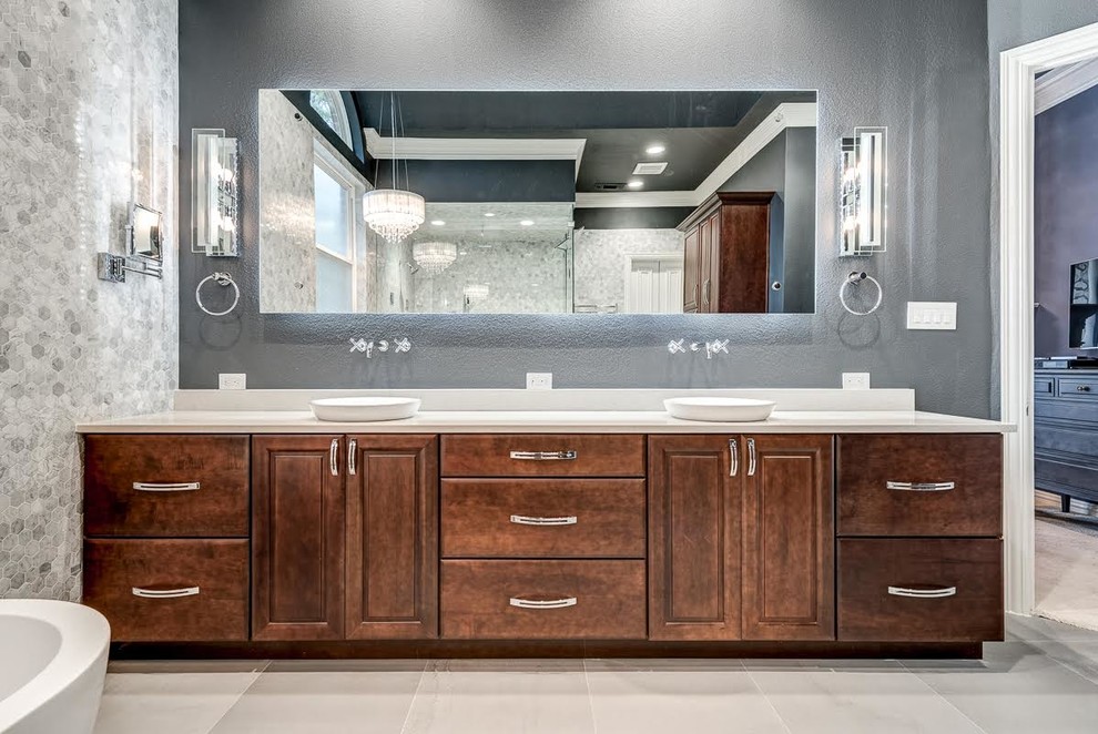 This is an example of a large contemporary master bathroom in Dallas with raised-panel cabinets, dark wood cabinets, a freestanding tub, a corner shower, a two-piece toilet, gray tile, marble, grey walls, ceramic floors, a vessel sink, solid surface benchtops, grey floor and a hinged shower door.