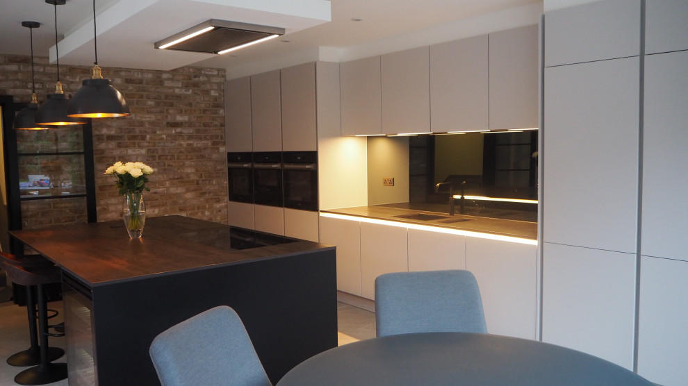 Mid-sized modern l-shaped separate kitchen in London with a drop-in sink, flat-panel cabinets, grey cabinets, metallic splashback, porcelain floors, with island, grey floor and brown benchtop.