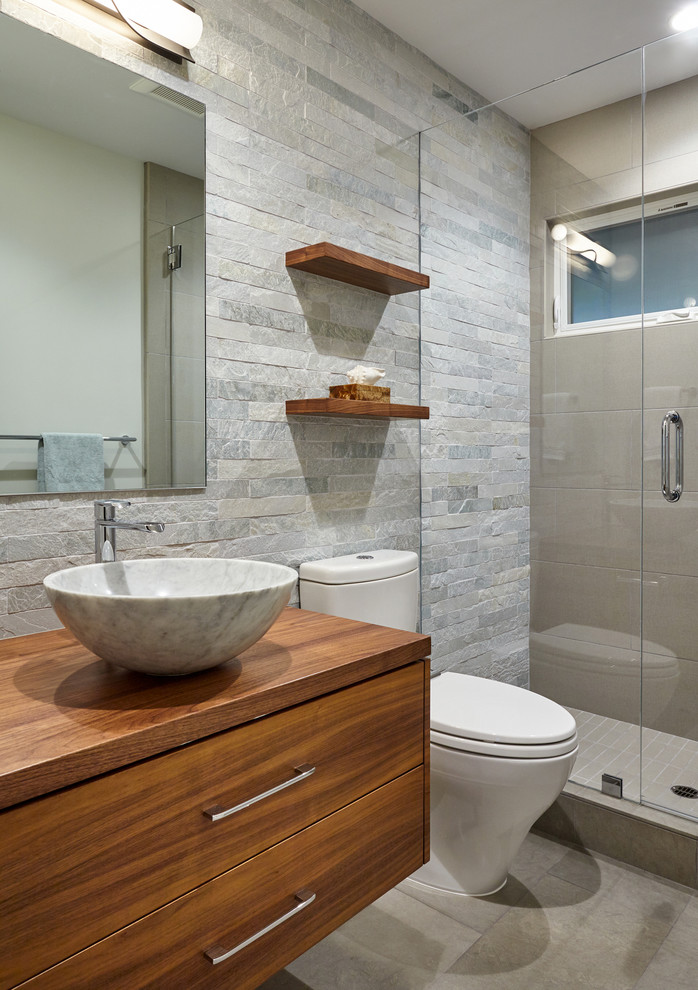 Small contemporary bathroom in San Francisco with flat-panel cabinets, medium wood cabinets, a two-piece toilet, green tile, stone tile, green walls, limestone floors, a vessel sink and wood benchtops.