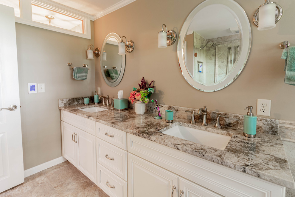 This is an example of a mid-sized traditional master bathroom in Other with raised-panel cabinets, white cabinets, a corner tub, a corner shower, a two-piece toilet, beige tile, porcelain tile, beige walls, porcelain floors, an undermount sink, granite benchtops, beige floor, a hinged shower door, beige benchtops, a shower seat, a double vanity, a built-in vanity and decorative wall panelling.