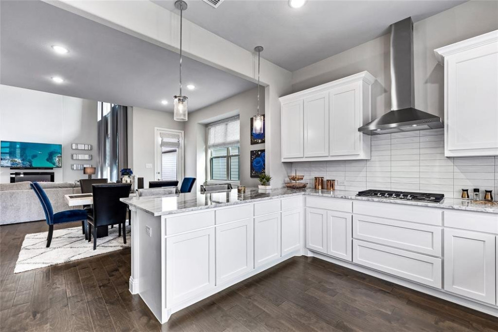 Inspiration for a mid-sized modern u-shaped eat-in kitchen in Houston with a drop-in sink, raised-panel cabinets, white cabinets, granite benchtops, white splashback, ceramic splashback, stainless steel appliances, dark hardwood floors, with island, brown floor, multi-coloured benchtop and recessed.