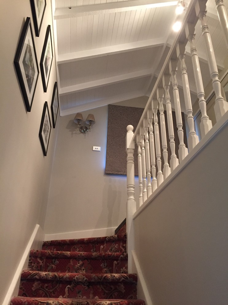 Design ideas for a mid-sized tropical carpeted l-shaped staircase in Sydney with carpet risers.