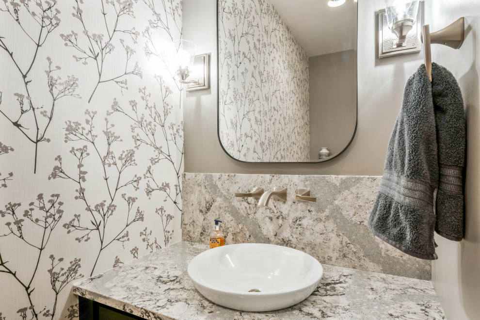 Design ideas for a small traditional powder room in Columbus with recessed-panel cabinets, black cabinets, a two-piece toilet, grey walls, medium hardwood floors, a vessel sink, engineered quartz benchtops, grey benchtops, a built-in vanity and wallpaper.