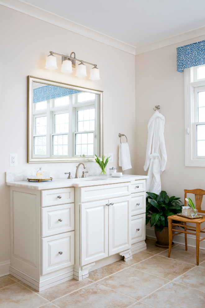 Photo of a large traditional master bathroom in DC Metro with raised-panel cabinets, white cabinets, a drop-in tub, an alcove shower, a two-piece toilet, beige tile, porcelain tile, white walls, porcelain floors, an undermount sink and quartzite benchtops.