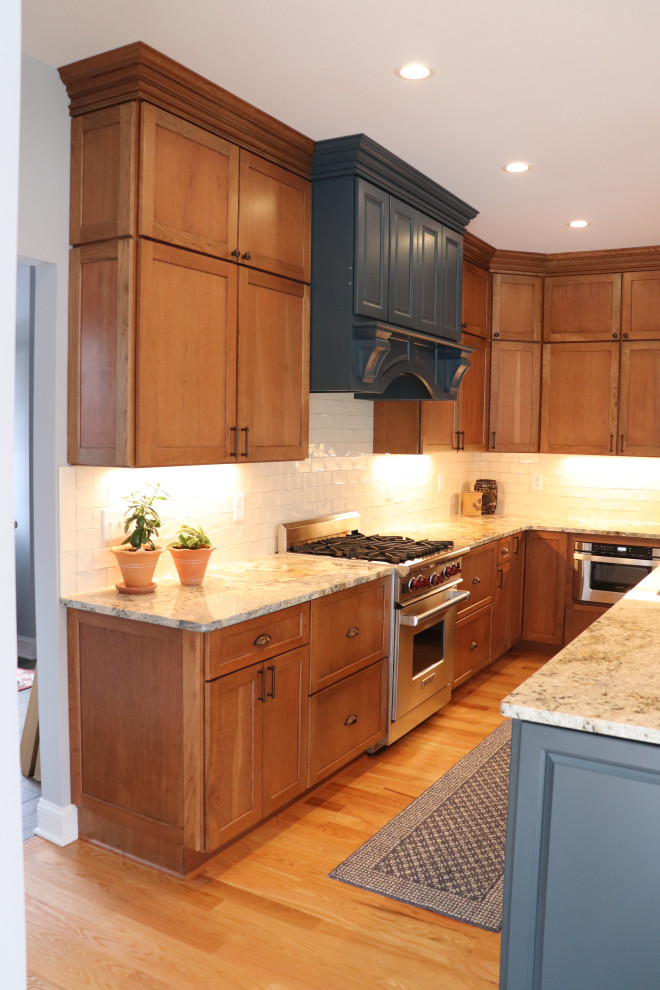Inspiration for an expansive transitional l-shaped eat-in kitchen in New York with an undermount sink, shaker cabinets, blue cabinets, granite benchtops, white splashback, ceramic splashback, stainless steel appliances, light hardwood floors, with island, yellow floor and grey benchtop.