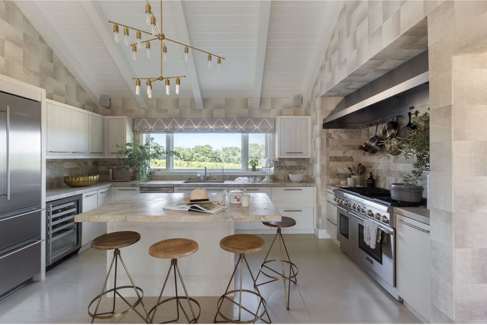 Inspiration for a large eclectic u-shaped open plan kitchen in San Francisco with an undermount sink, flat-panel cabinets, white cabinets, marble benchtops, beige splashback, stone tile splashback, stainless steel appliances, concrete floors and with island.