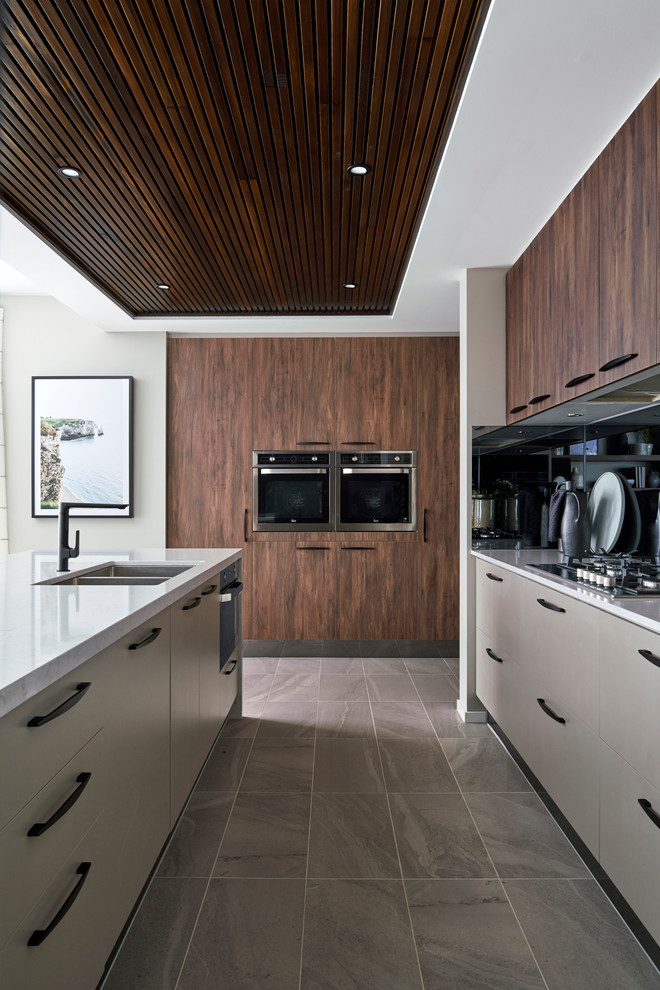 Beach style u-shaped open plan kitchen in Other with medium wood cabinets, black splashback, with island, grey floor and white benchtop.