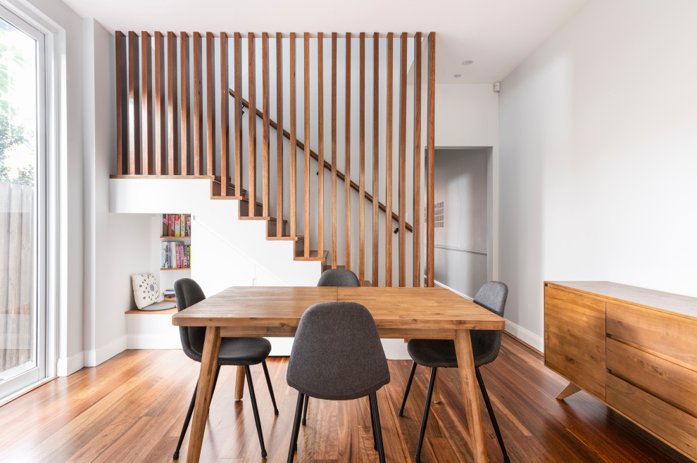 This is an example of a mid-sized contemporary kitchen/dining combo in Sydney with white walls, medium hardwood floors, no fireplace and brown floor.
