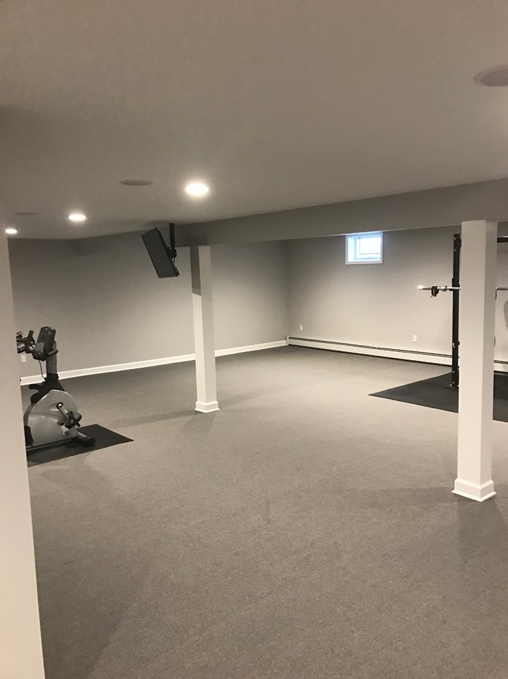 This is an example of a large traditional home weight room in New York with grey walls, carpet and grey floor.