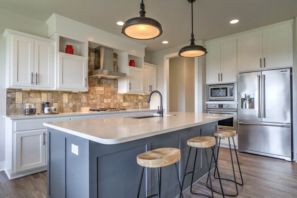 Inspiration for a transitional open plan kitchen in Omaha with an undermount sink, shaker cabinets, quartzite benchtops, brick splashback, stainless steel appliances, with island, white cabinets, beige splashback, medium hardwood floors and brown floor.