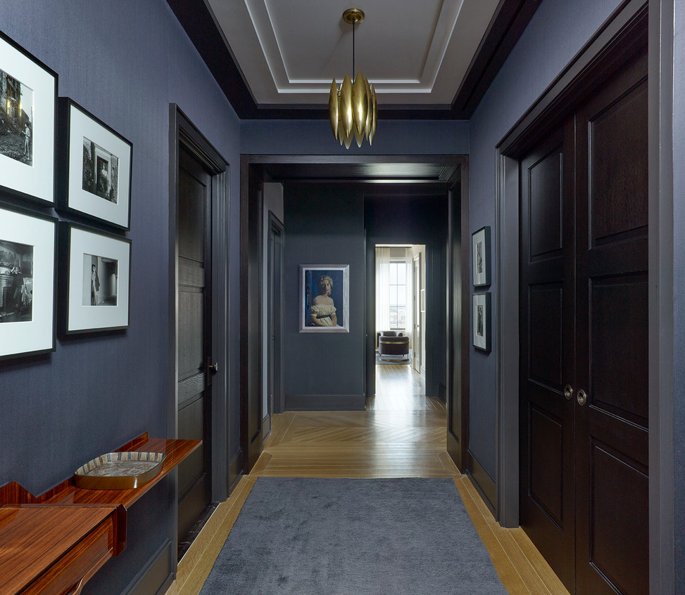 Photo of a mid-sized contemporary entry hall in New York with grey walls, light hardwood floors, a single front door, a gray front door and beige floor.