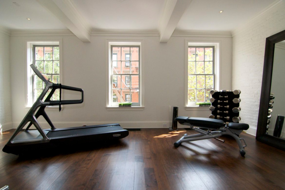 Cette photo montre une salle de musculation chic de taille moyenne avec un mur blanc, un sol en bois brun, un sol marron et un plafond à caissons.