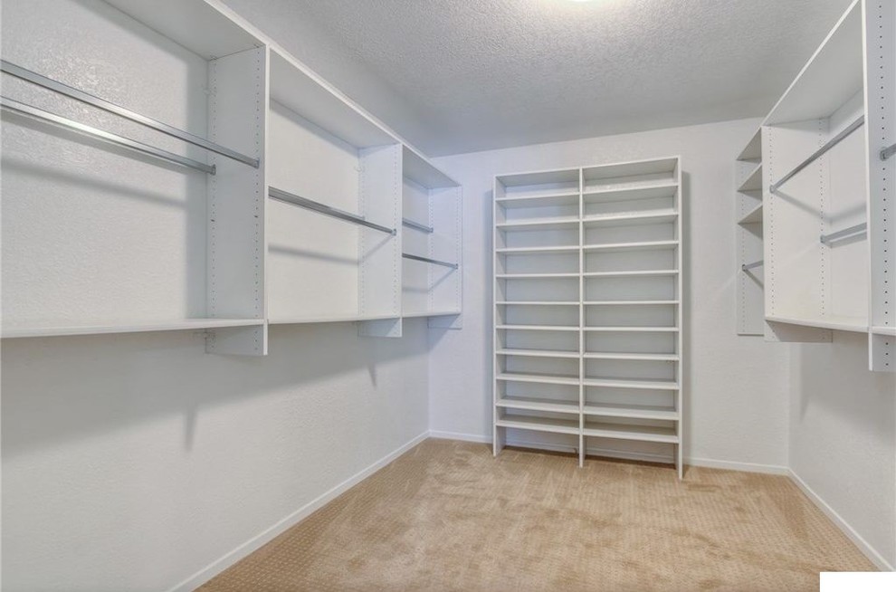 Photo of a small modern gender-neutral walk-in wardrobe in Los Angeles with open cabinets, white cabinets, carpet and beige floor.